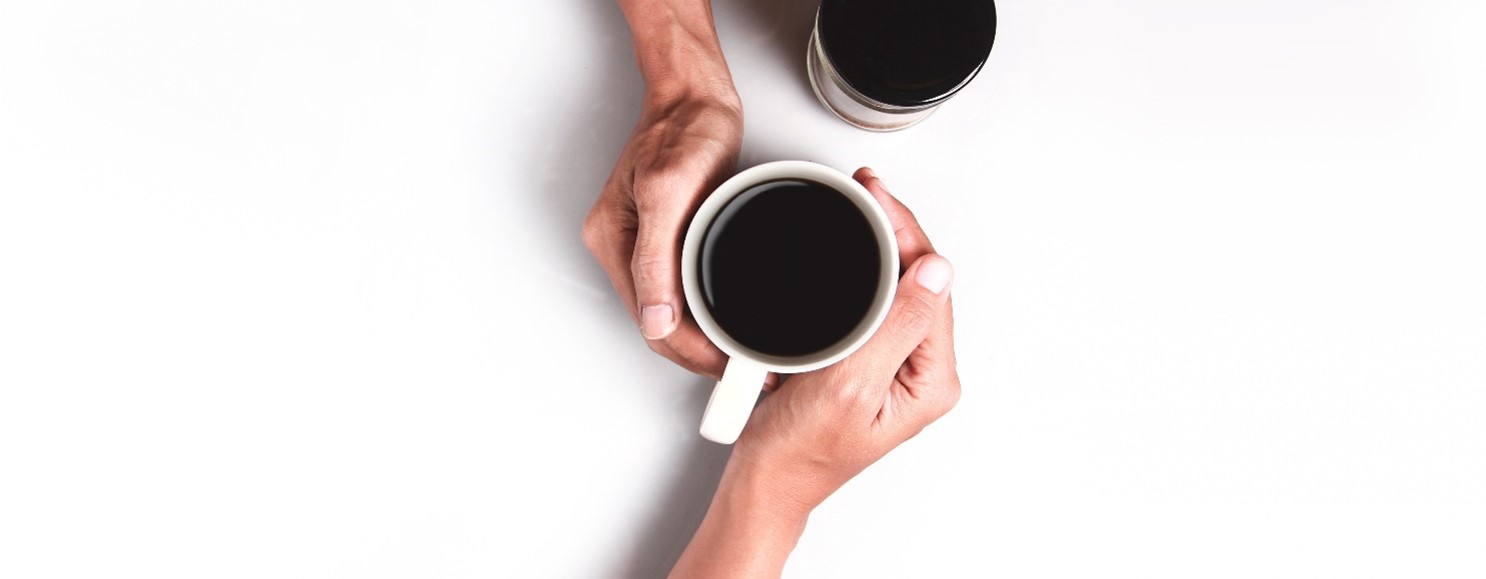 Two hands joined around a cup of coffee