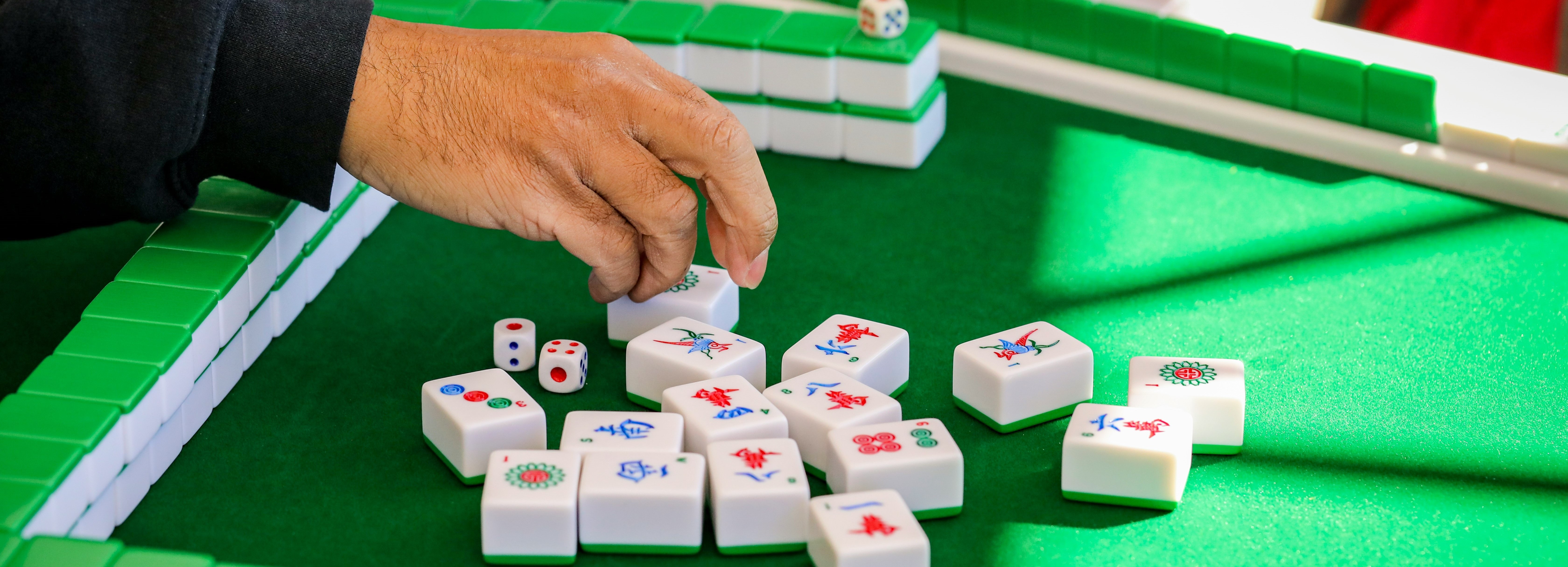 hand holding mahjong tiles on green table