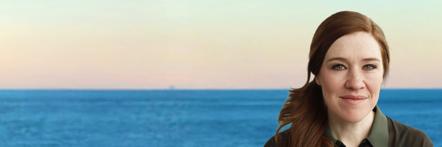 A headshot of Clara Hughes in front of a ocean horizon background.