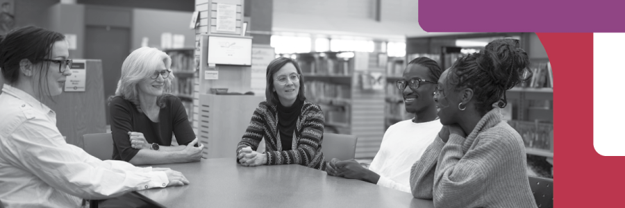 Group of people sitting around a table in a library having a discussion