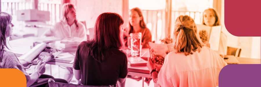 Adults sitting around a table holding cookbooks and talking.