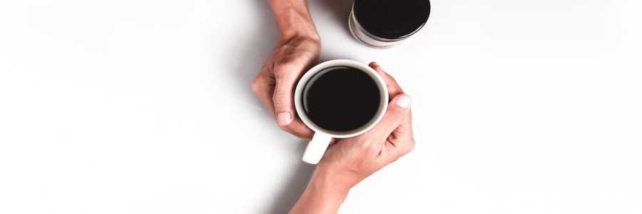 Two hands joined around a cup of coffee
