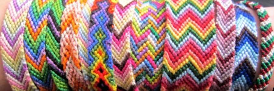 a row of colourful friendship bracelets made of knotted thread