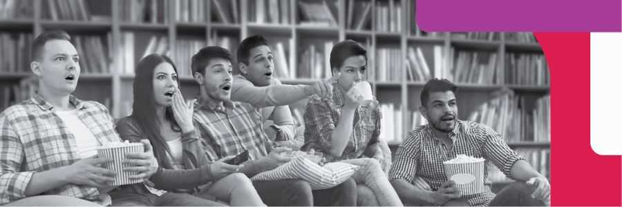 A group of adults sit together on a couch, watching a film.