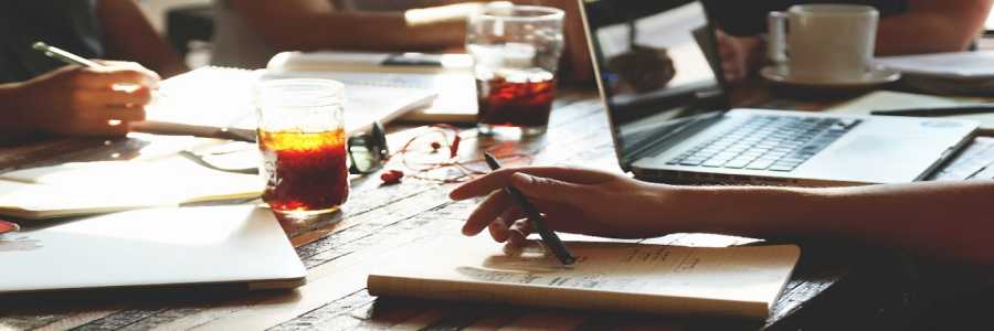people writing in notebooks and laptops on tabletop