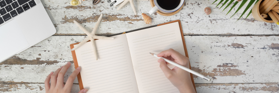person writing in a notebook at a desk